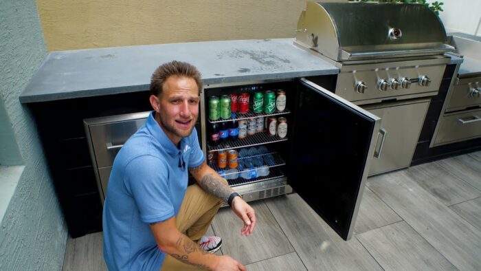 an outdoor kitchen designer in front of a coyote 24 inch refrigerator