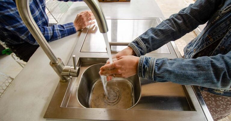 woman washing her hands in a coyote refreshment center in rta outdoor kitchen
