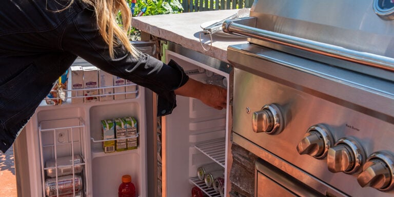 Best outdoor refrigerator with a woman grabbing drink of one in rta outdoor kitchen
