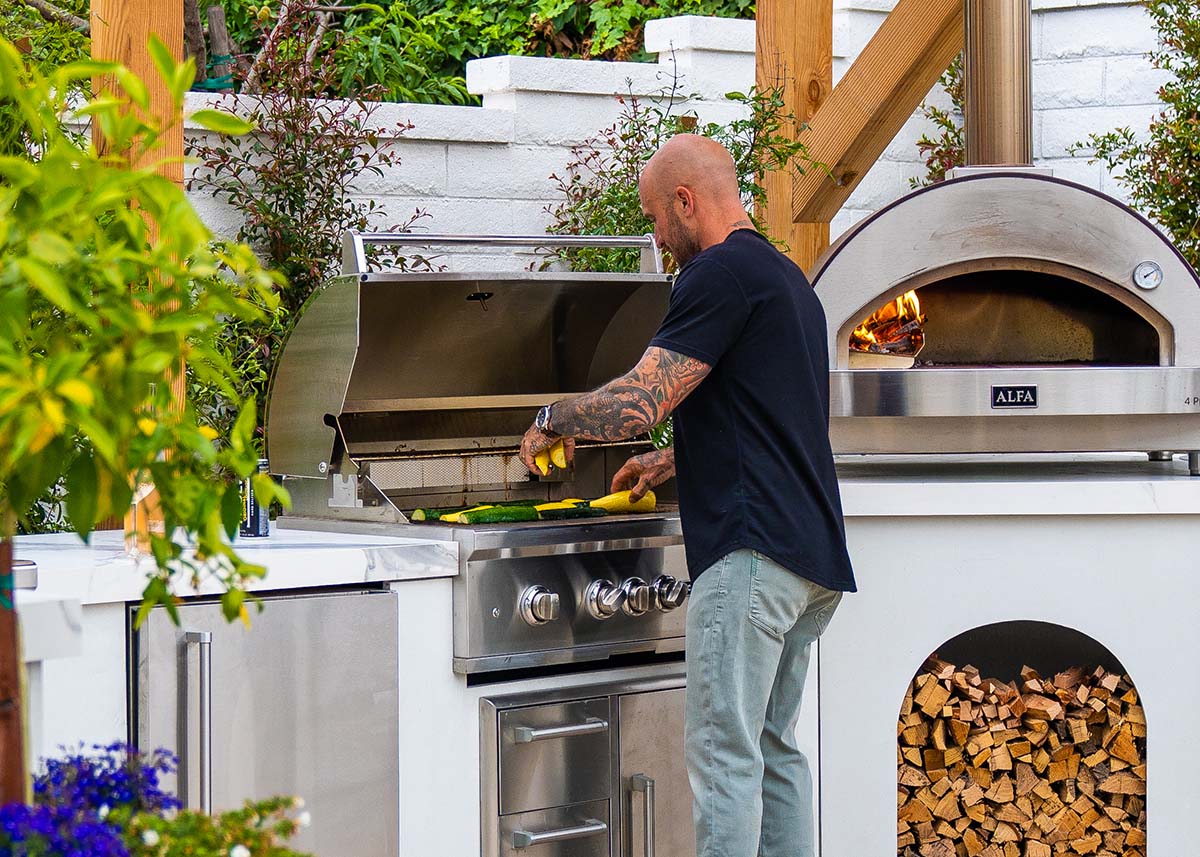 man grilling on an outdoor kitchen with gas grill