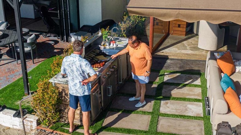 men grilling food at outdoor kitchen on patio