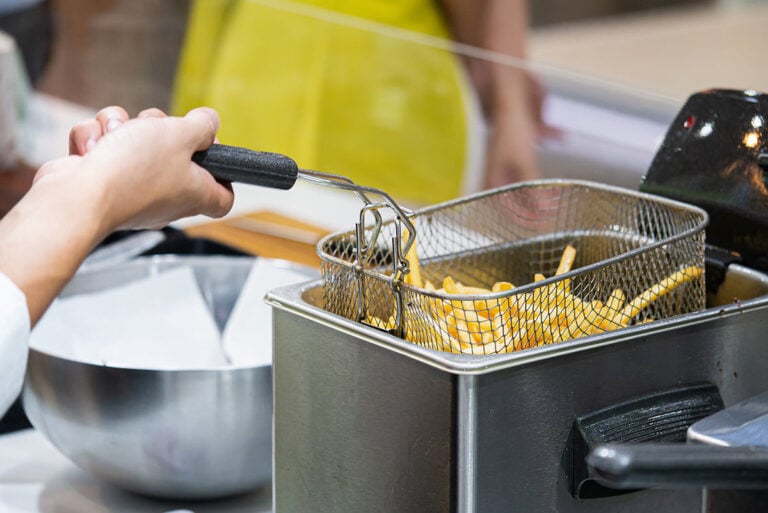 person taking basket out of deep fryer