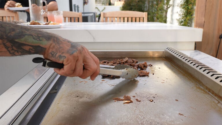 man cooking meat on flat top grill