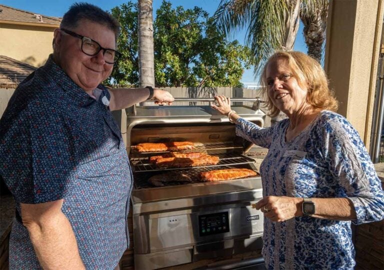 couple using their built in coyote pellet grill