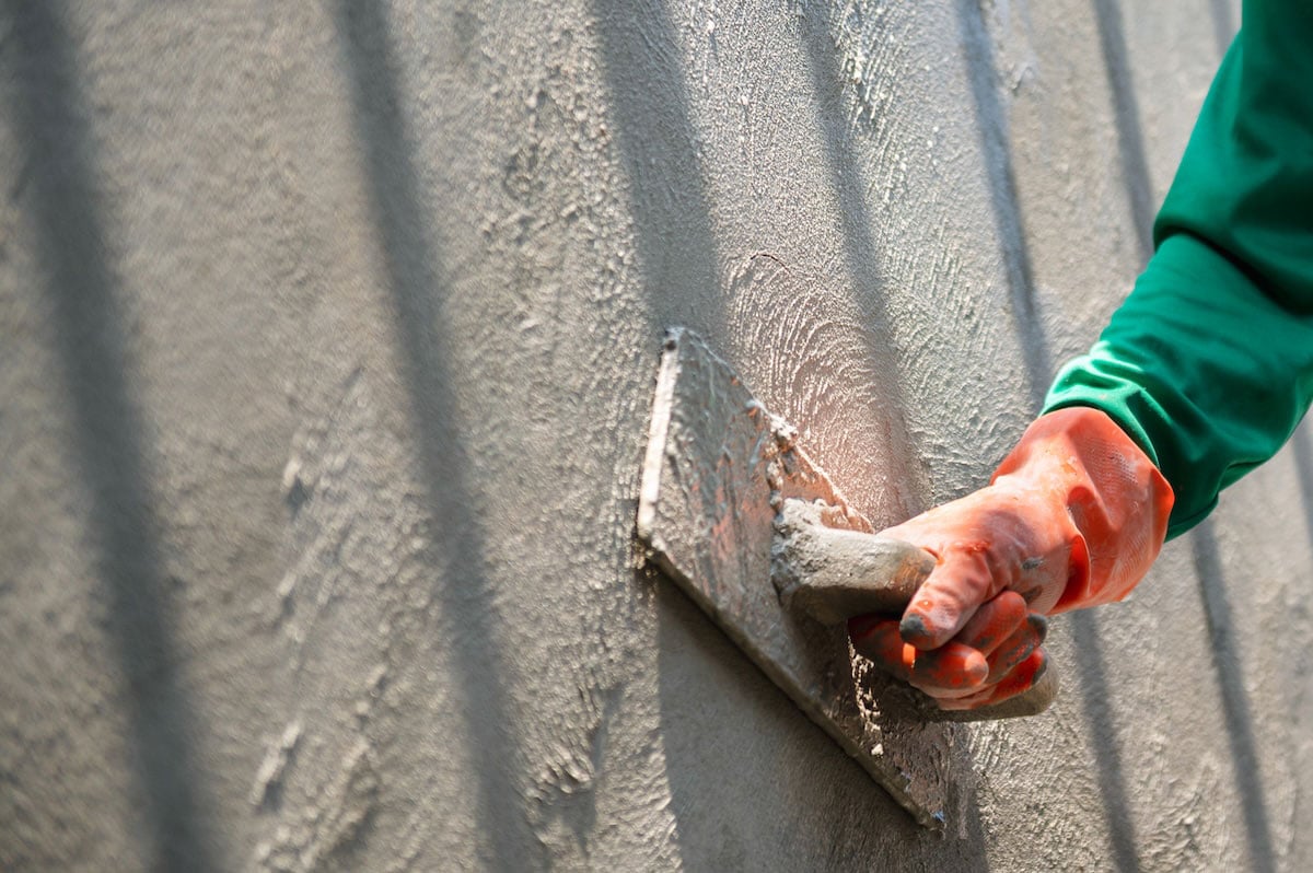 man applying stucco layers to outdoor kitchen