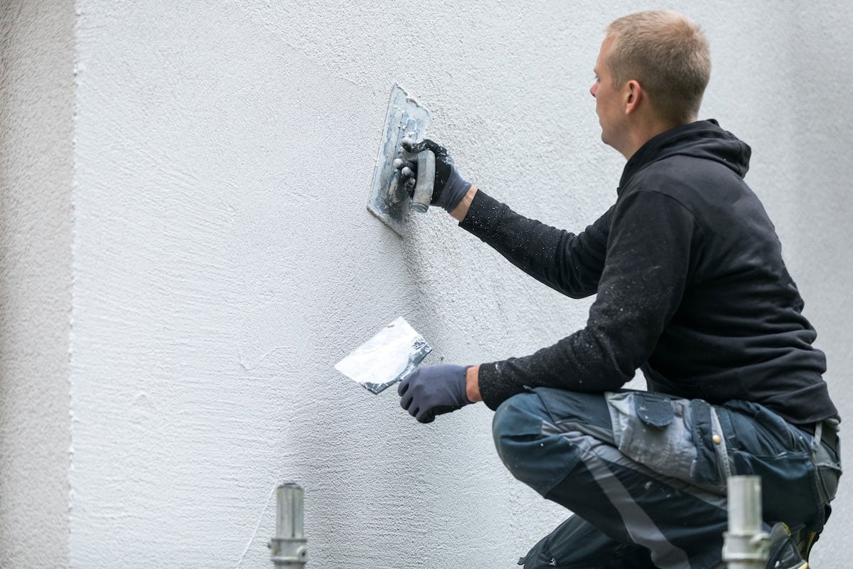 man applying stucco to the side of an outdoor kitchen