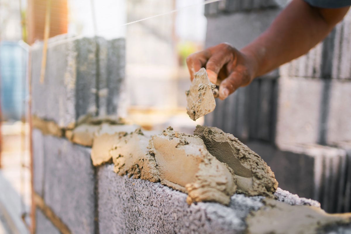man laying cinder blocks for outdoor kitchen