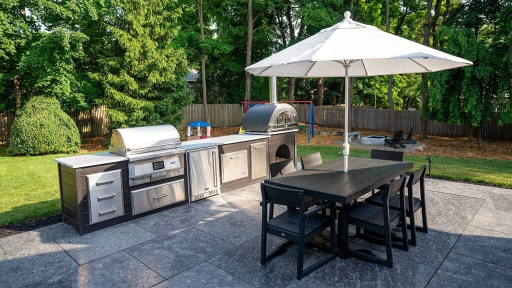 RTA outdoor kitchen on a patio with a dining table and umbrella